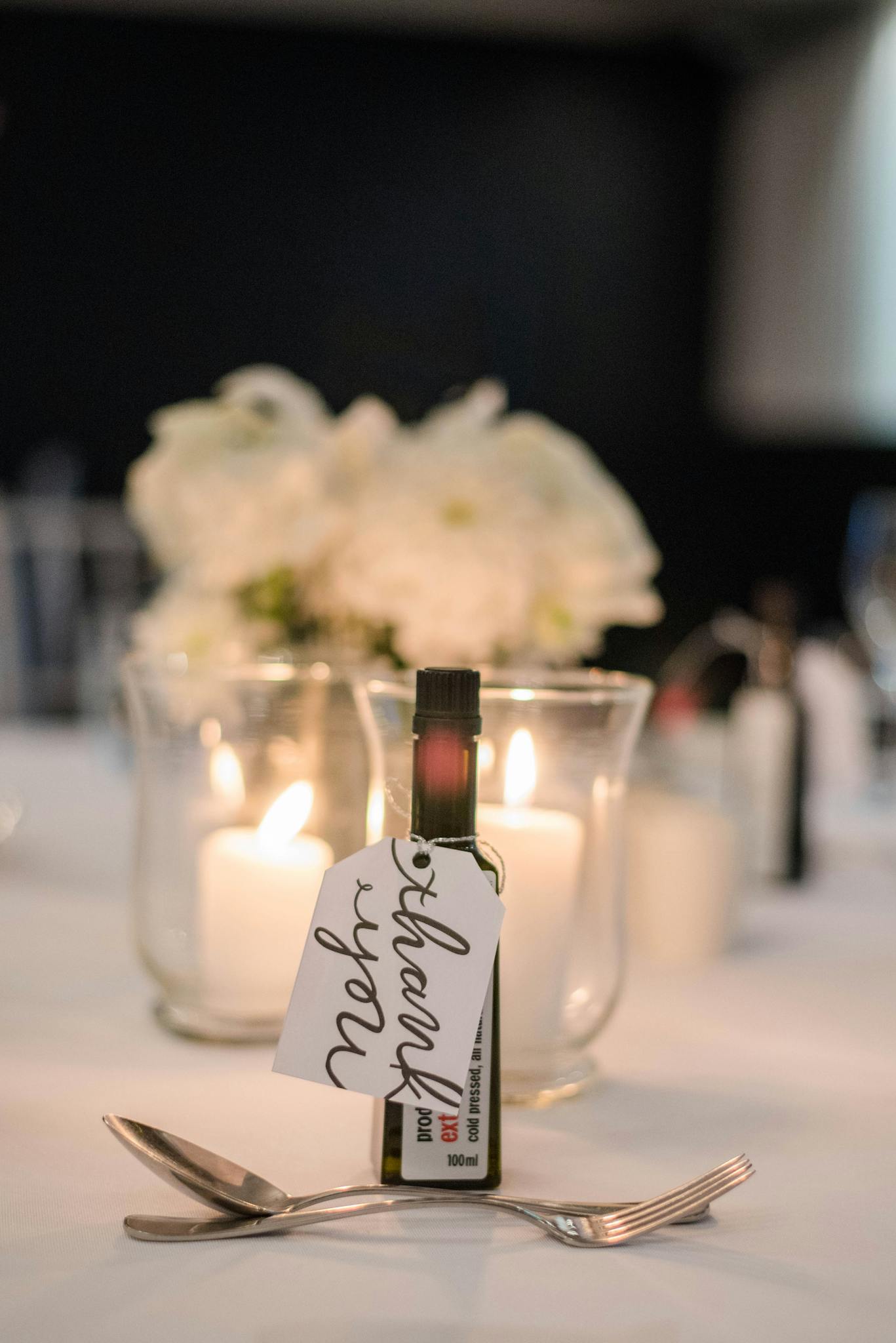 Composition of banquet table with dessert cutlery on white cloth decorated with delicate white flowers and burning candles in glass holders